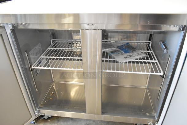 Brand new Avantco 178SSPT36HC stainless steel prep table with double doors, two wire shelves, minor scratches, on casters.