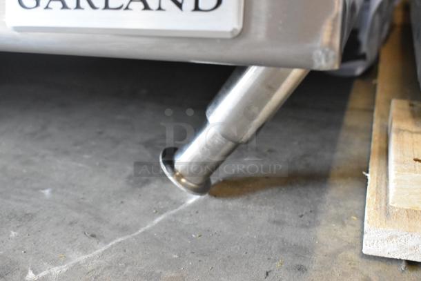 Garland stainless steel countertop gas griddle leg, brand new with minor scratches and dents visible.