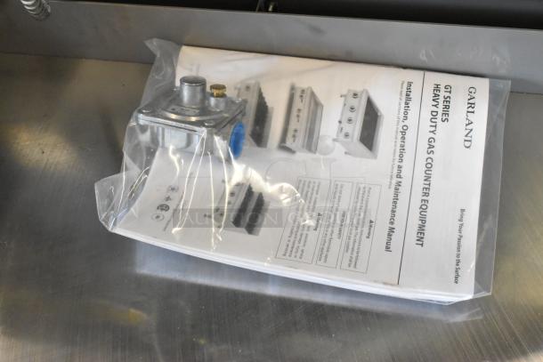 Garland stainless steel gas griddle manual and part in packaging, indicating new condition despite minor scratches or dents.