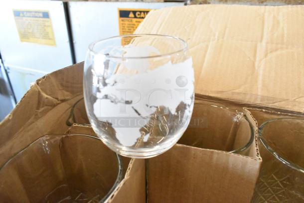 Box of various glasses, including one with etched world map design. Set in cardboard packaging, appears in good condition.