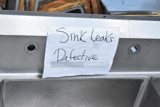 Yukon stainless steel 3 bay sink with dual drain boards, no legs. Note indicates defective and leaking condition.