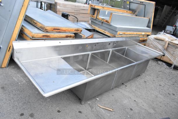 Yukon stainless steel 3 bay sink with dual drain boards, no legs. Slight wear visible, ideal for commercial use.