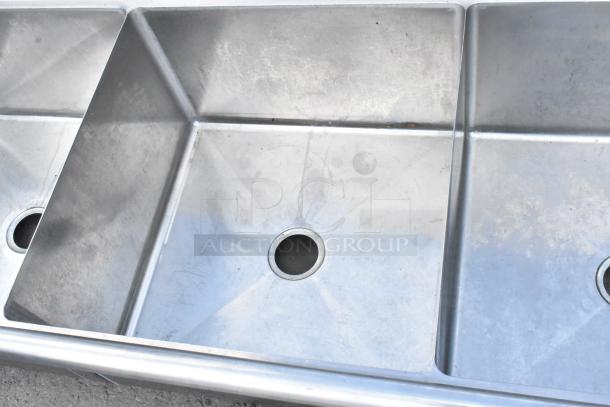 Yukon stainless steel 3 bay sink with dual drain boards, no legs, used condition, visible drain holes.