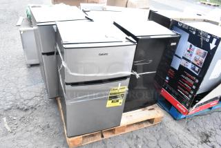 Four mini coolers including Galanz GLR31TS1E02 shown on a pallet. Visible Energy Guide on one unit, wrapped for shipment.