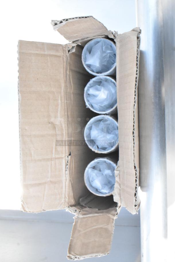 Cardboard box containing four wrapped tubes, with a stainless steel item partially visible.