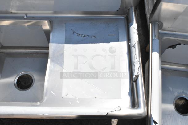 Stainless steel Regency 600S31515215 three bay sink with dual drain boards, scratch and dent condition, visible damage.
