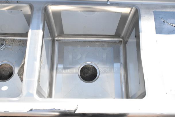 BRAND NEW Regency 600S31515215 stainless steel 3-bay sink with dual drain boards; slight scratches visible.