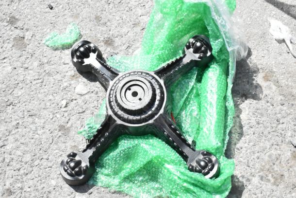 New table leg base, black with ornate design, partially wrapped in green bubble wrap, minor scratches visible.
