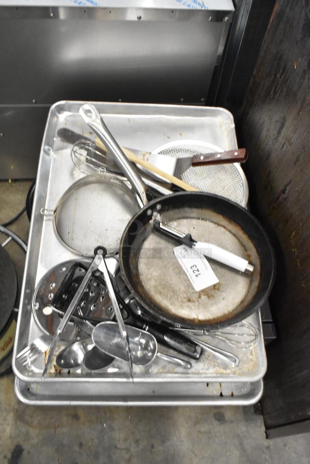 Lot of kitchen items, including a worn skillet and various utensils on trays. Tag labeled "123".