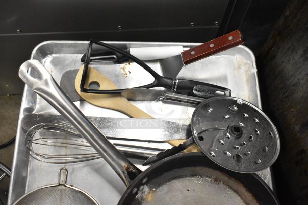 Lot of kitchen items including skillet, metal whisk, wooden spatula, tongs, and Cuisinart peeler. Used condition.
