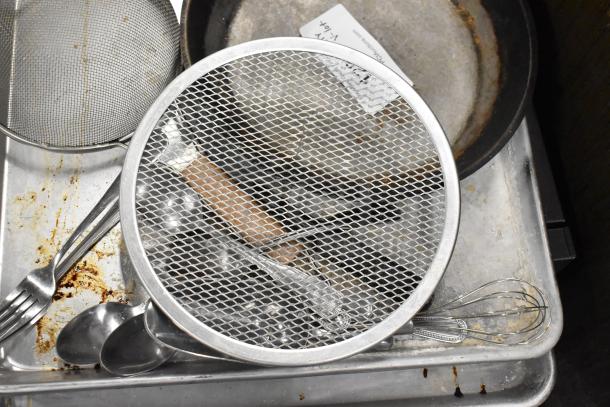 Lot of kitchen items including a skillet, mesh strainers, utensils, and a baking sheet. Moderate wear, ideal for culinary use.