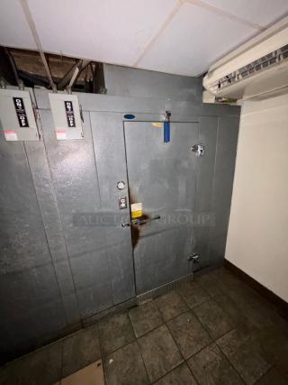 6'x8' Norlake walk-in cooler with self-contained compressor and condenser. Features metal door with latch, showing signs of wear.