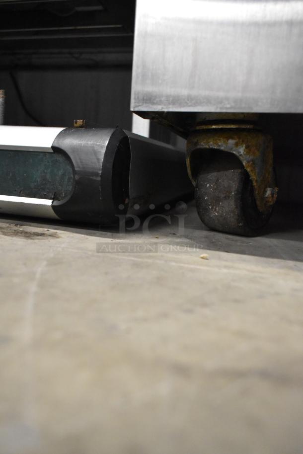 Close-up of the base and caster of a Taylor C723-33 stainless steel soft serve ice cream machine, showing wear on the caster.