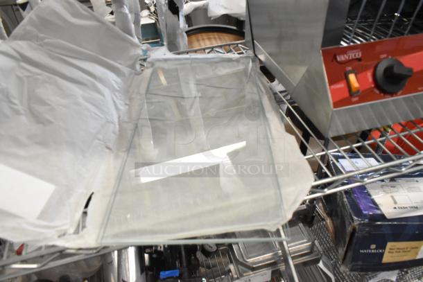 Two new scratch and dent glass panes on a metal shelf, partially wrapped in paper, ready for auction.