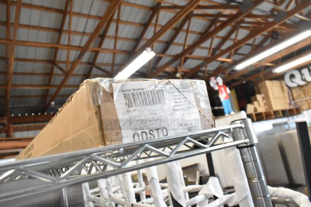 Brown cardboard box with label, on a metal shelf, in a warehouse setting. Box contains Hatco GRAH-60 Infrared Food Warmer.
