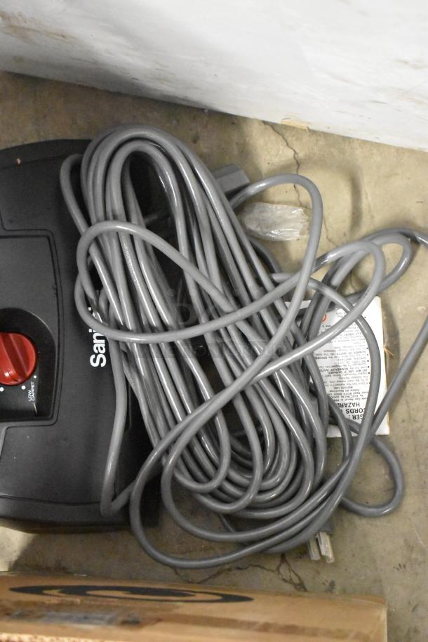 BRAND NEW Sanitaire SC9180D vacuum with coiled power cord, red dial, visible branding, and scratch marks. 120V, 1 phase.