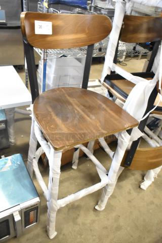New Lancaster black metal bar height chair with wooden back and seat, wrapped for protection. Scratch and dent condition.