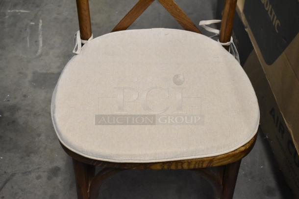 Wooden dining chair with cross back, tan seat cushion, brand new, scratch and dent condition.