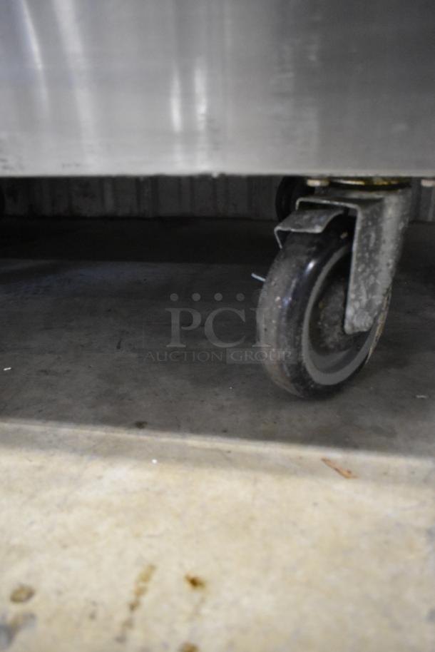 Stainless steel caster of Standard Range SR-R36 commercial gas range, showing part of the wheel on a concrete floor.