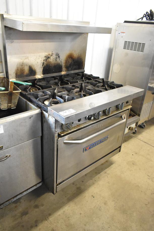 Bakers Pride stainless steel 6-burner range with oven, over shelf, and backsplash. Gas-powered, commercial use, visible wear.