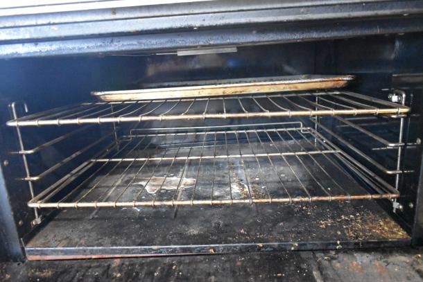 Bakers Pride stainless steel commercial gas range oven interior showing two racks and baking tray, used condition.