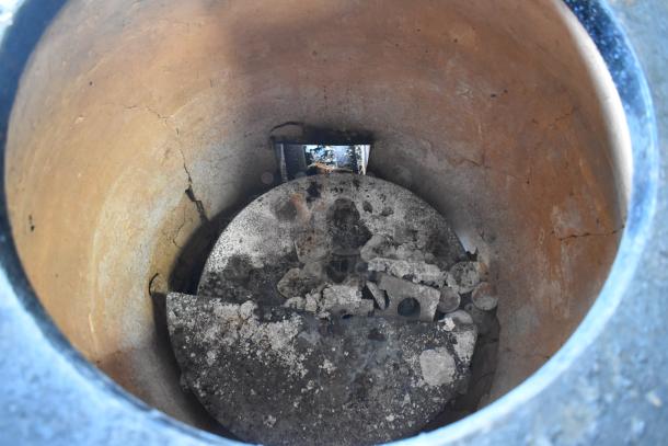 Stainless steel gas-powered tandoor oven interior view, showing wear and ash buildup. Includes commercial casters.
