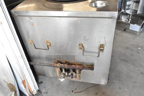Stainless steel gas-powered tandoor oven on casters, showing signs of wear. Features include handles and a circular cooking surface.