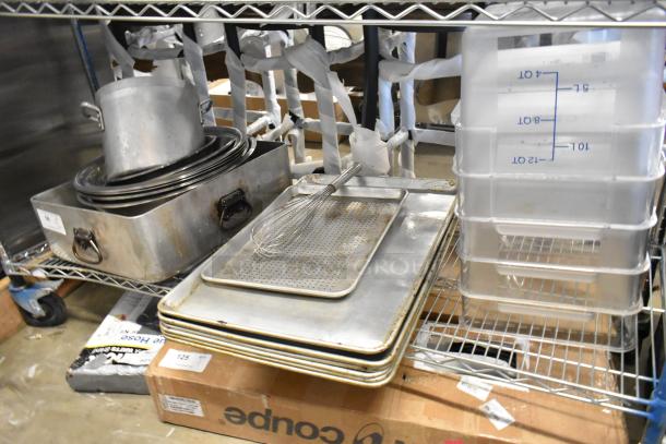 Tier lot of metal baking pans, poly containers with volume markings, and a large metal pot, all in used condition.