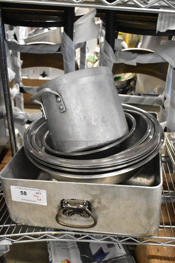 Various metal baking pans and a pot stacked in a square metal container. Visible tag reads "58 QTY Tier lot." Slightly worn condition.