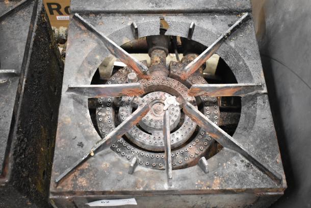 Metal commercial gas-powered single burner stock pot range, showing visible wear, sturdy construction, and sealed burners.