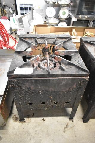 Metal commercial gas-powered single burner stock pot range, visible surface wear, rust on burner, label "63".