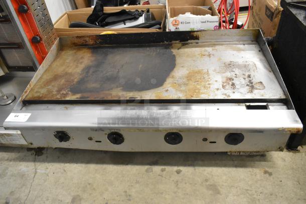 Stainless steel commercial countertop gas griddle, showing signs of wear and rust, with visible control knobs.