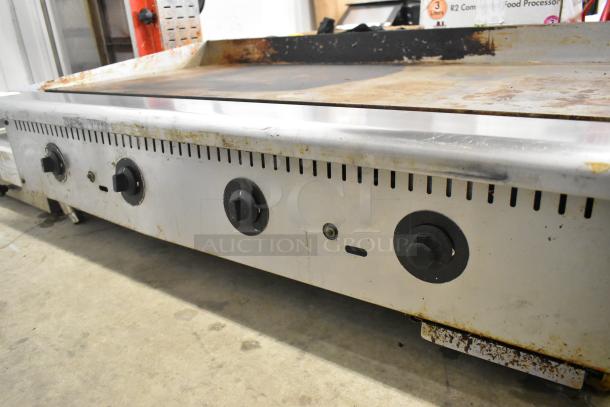 Stainless steel countertop gas griddle, used condition, features three control knobs, with rust on edges.