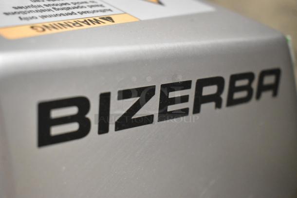 2023 Bizerba GSP H metal commercial meat slicer, 120 volts, 1 phase. Close-up of Bizerba logo on silver surface.