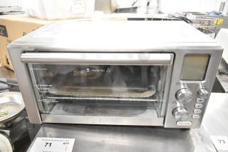 Metal countertop electric toaster oven, 120 volts, 1 phase. Features multiple cooking modes and digital controls. Visible wear.