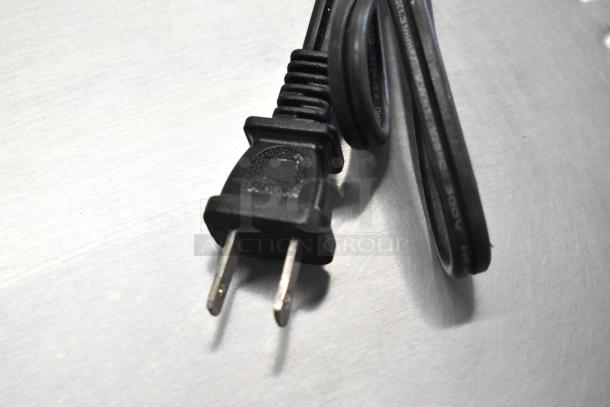Power cord with a standard plug for a metal countertop electric toaster oven, 120 volts, 1 phase, shown coiled on a metal surface.
