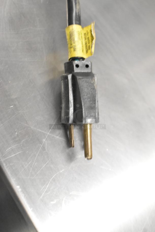 Close-up of a two-prong plug for the Bunn VP17-3 coffee machine. The plug features a yellow caution label.