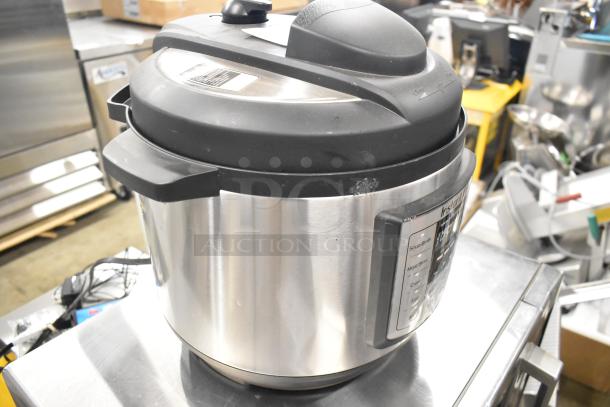 Instant Pot Lux 80 metal countertop pressure cooker, 120 volts, with black lid. Slight wear visible on stainless steel body.