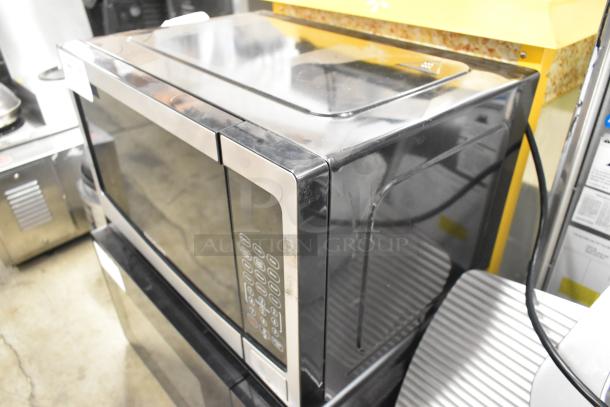 Frigidaire EMW1120-B-3ACOM stainless steel countertop microwave oven. Features keypad controls, visible wear. 120 volts, 1 phase.