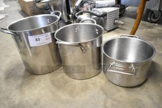 Three metal stock pots in varying sizes with handles, shown in good condition. Visible auction label: "PCI Auctions, 83."