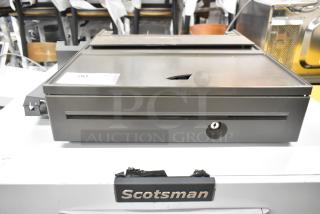Gray metal cash drawer, featuring a lock and key slot. Minor surface wear, indicating use. Label with number 90 attached.