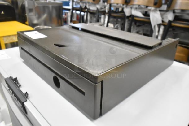 Gray metal cash drawer, rectangular design, sturdy construction, slightly used condition, no visible labels.