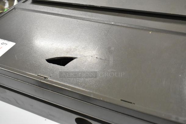 Gray metal cash drawer, visible surface scratches, small tear on top. Features a storage compartment. Label indicates quantity.