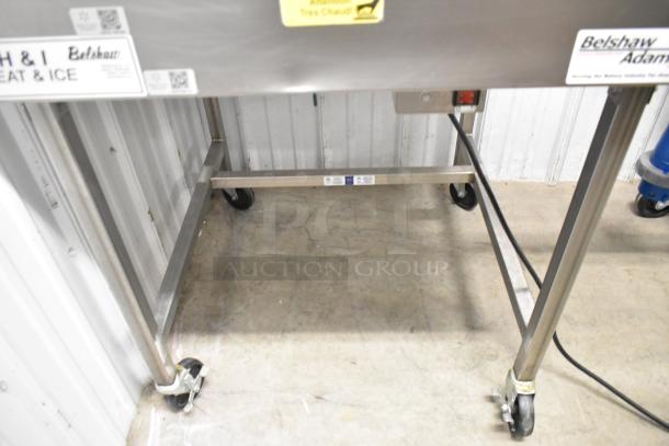Belshaw Adamatic H&I stainless steel glazing station with commercial casters, features visible labels and solid condition.