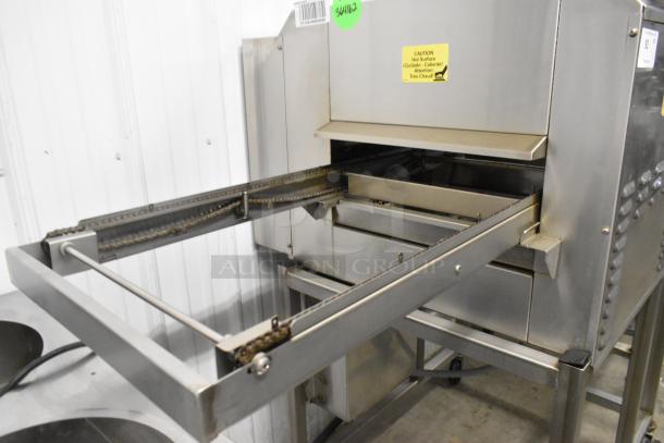 Belshaw TG50 stainless steel thermoglazing station, floor style, commercial casters, 208 volts, visible caution label.