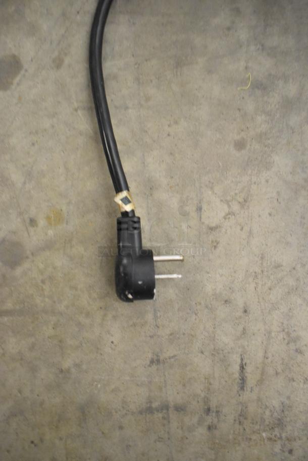 Power cord for Belshaw Adamatic H&I-4 Glazing Station, black plug, standard prongs, on a textured gray surface.