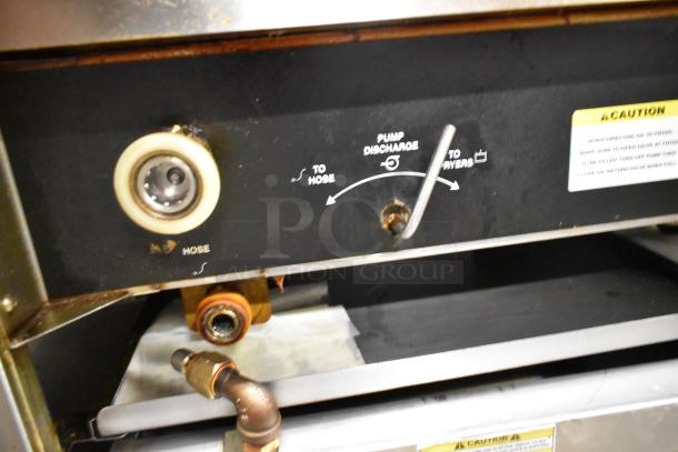 Giles EOF-24 stainless steel commercial electric fryer with center dumping station. Features visible pump discharge lever, caution labels, and hose connection. Operates at 480 volts, 3 phase. Mounted on commercial casters.