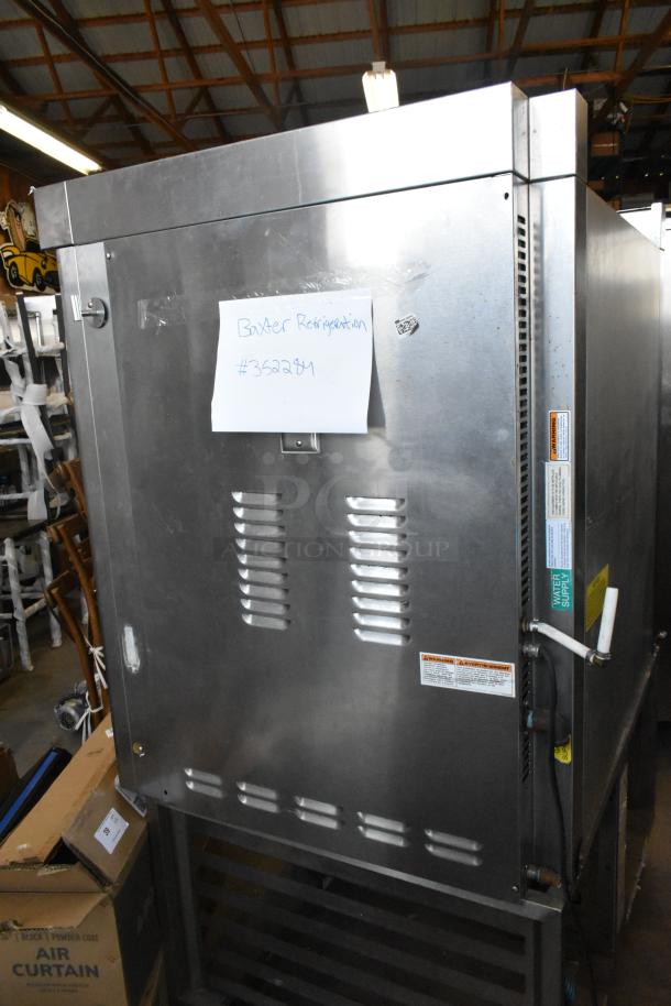 Baxter stainless steel commercial natural gas mini rotating rack oven with dual pan rack, on casters. Visible warning labels.