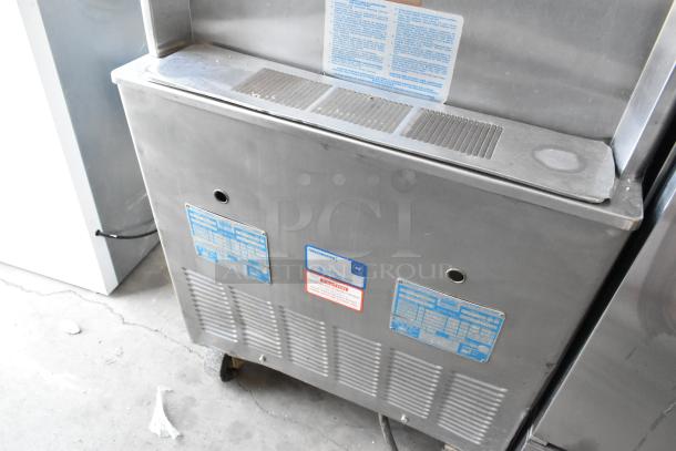 Taylor 754-27 stainless steel commercial soft serve ice cream machine with casters; dual flavor with twist, 208/230V, 1 phase. Tags visible.