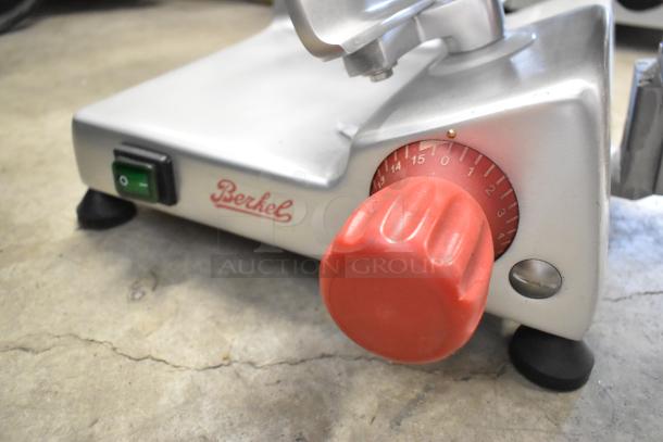 Berkel B9-SLC stainless steel meat slicer with blade sharpener, 115V, 1 phase. Features red adjustment dial and green power switch.